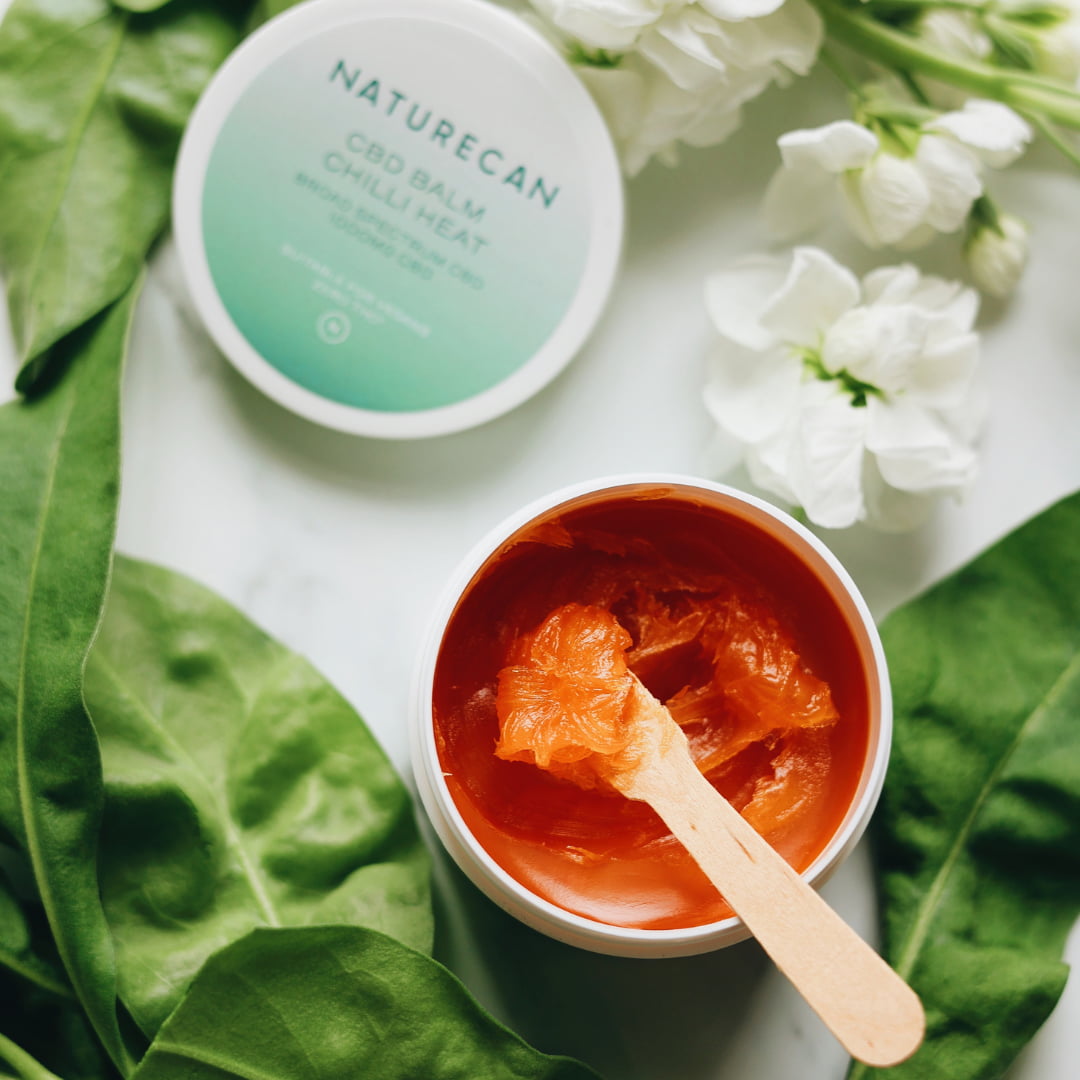 Balsam do mięśni Chilli Heat CBD Naturecan w otwartym słoiczku, widoczna konsystencja i drewniana szpatułka