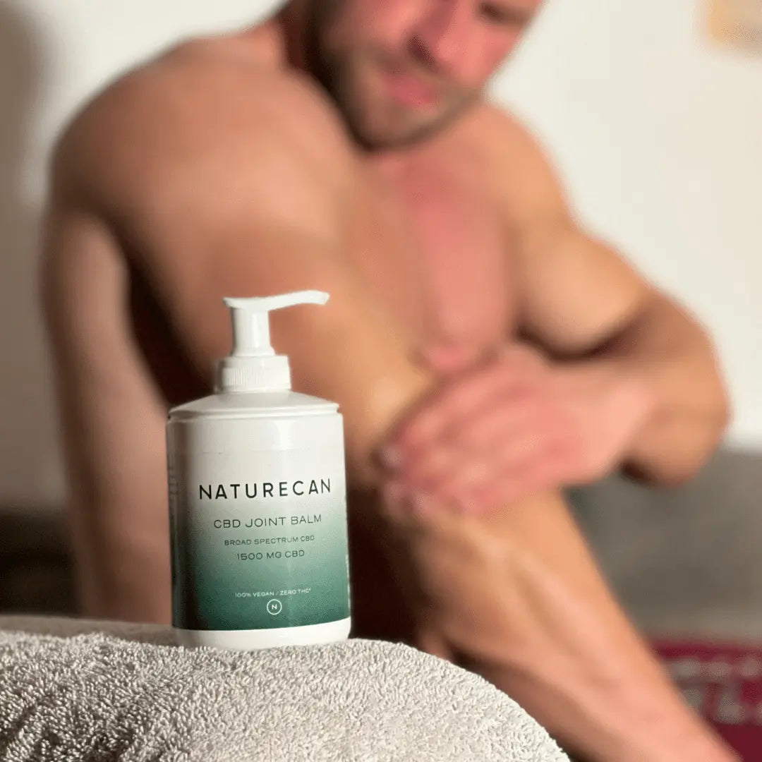 Mężczyzna nakłada balsam na stawy CBD Naturecan na łokieć po wysiłku.