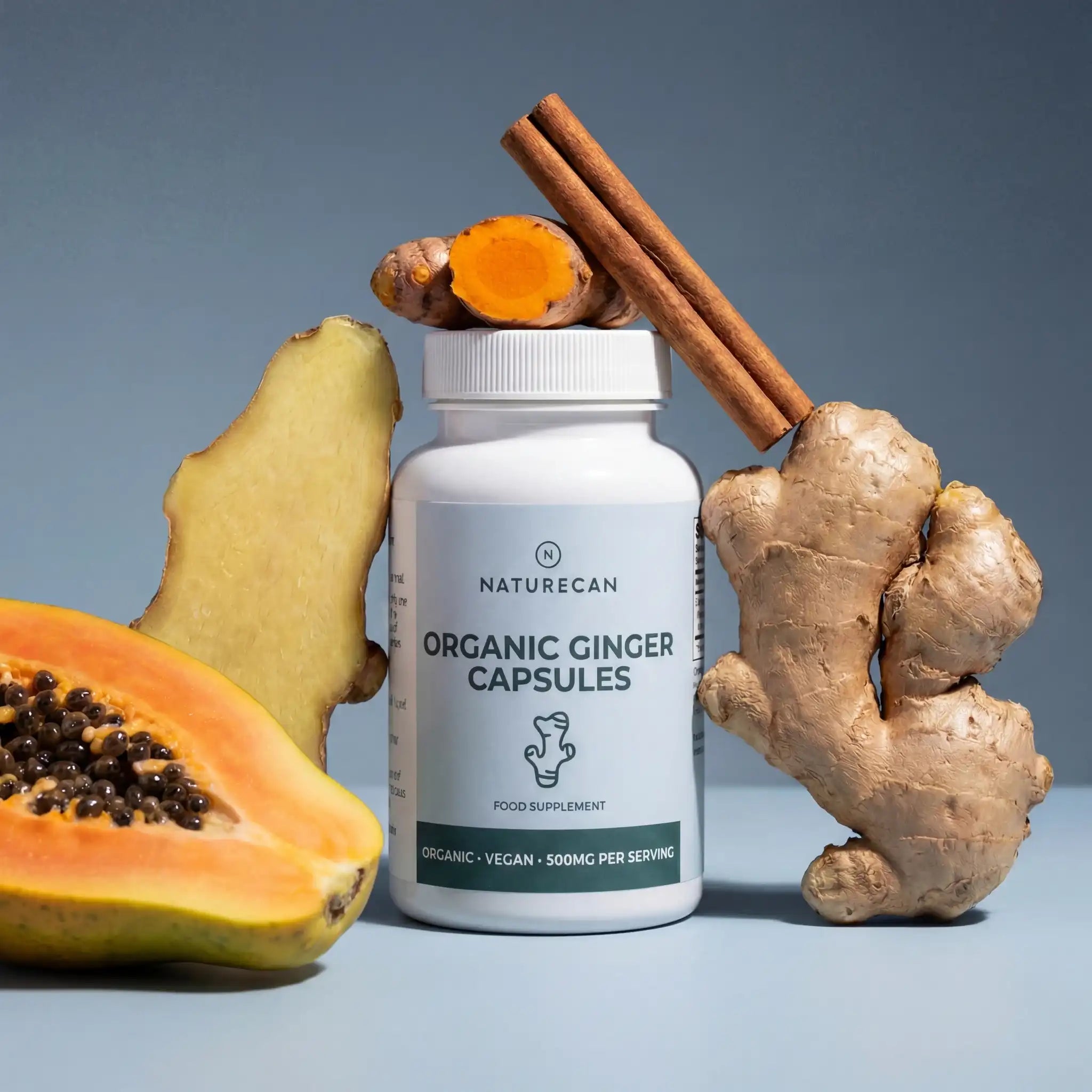 Organiczny imbir w kapsułkach 500 mg Naturecan na tle świeżego imbiru, kurkumy i cynamonu – naturalne wsparcie trawienia