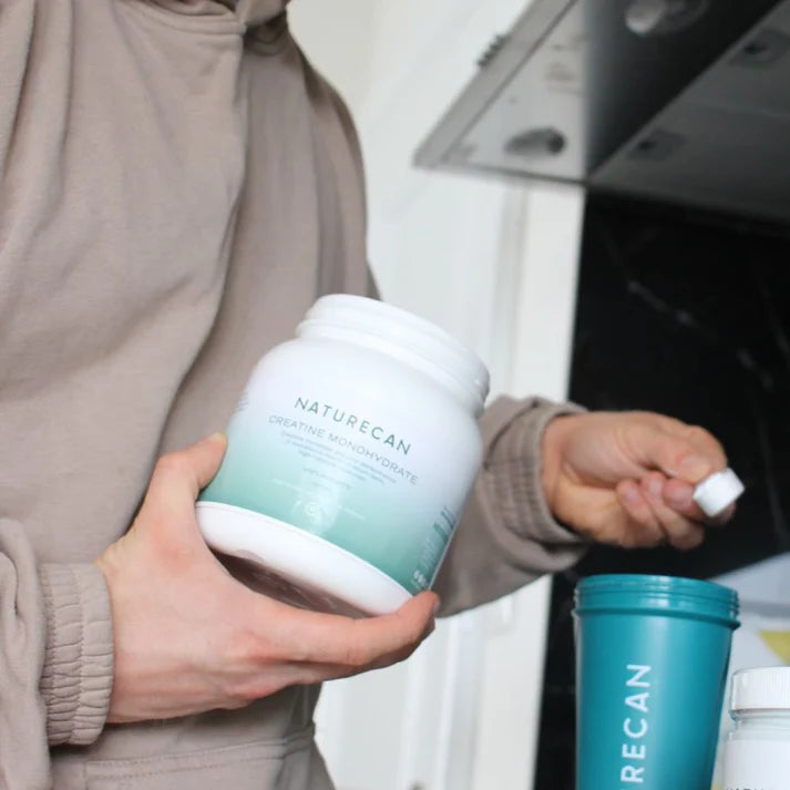 Osoba odmierzająca porcję Naturecan Kreatynę Monohydrat w kuchni – kreatyna łatwa do przygotowania, idealna do codziennej suplementacji.