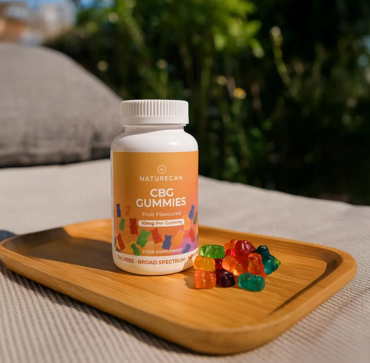 Owocowe żelki CBG 10 mg Naturecan – opakowanie i kolorowe żelki na drewnianej tacy w naturalnej aranżacji.